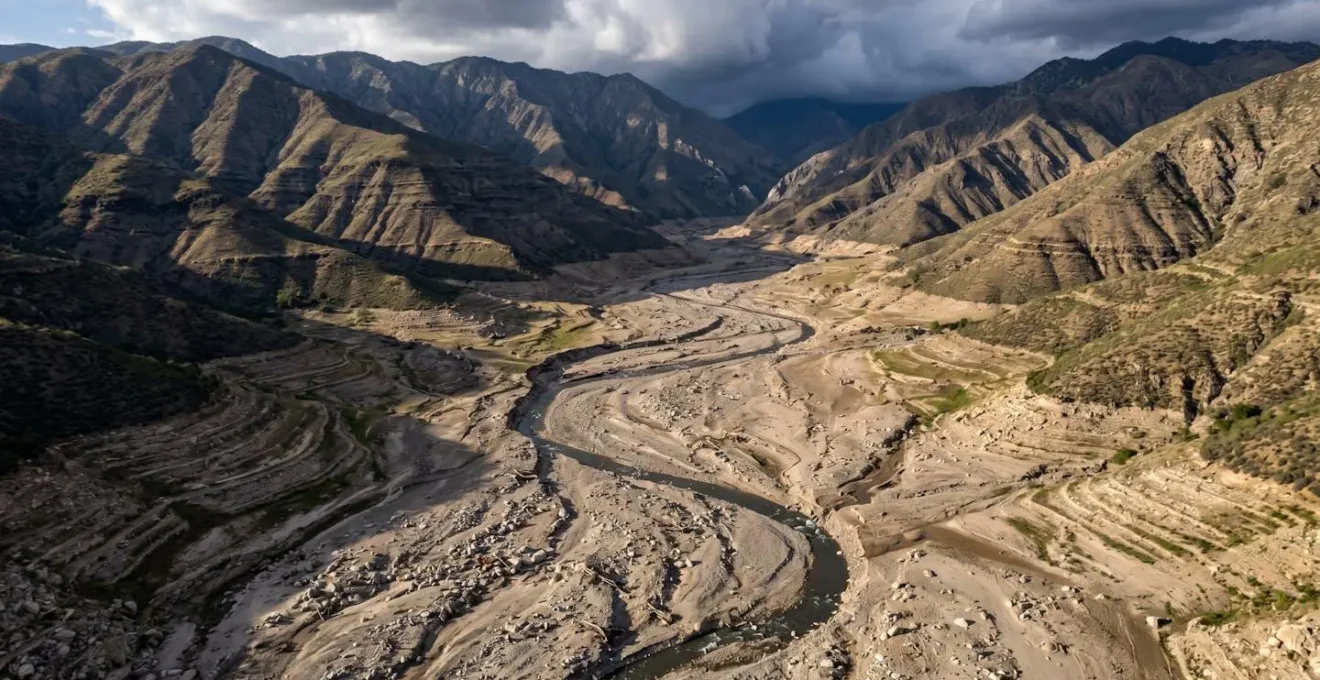Vue aérienne d'un lit de rivière asséché en montagne montrant les traces d'anciennes crues