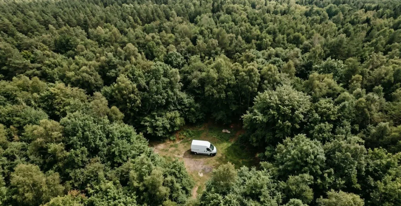 Vue plongeante d'un van isolé dans la nature entouré de verdure, stationnement paisible loin des routes