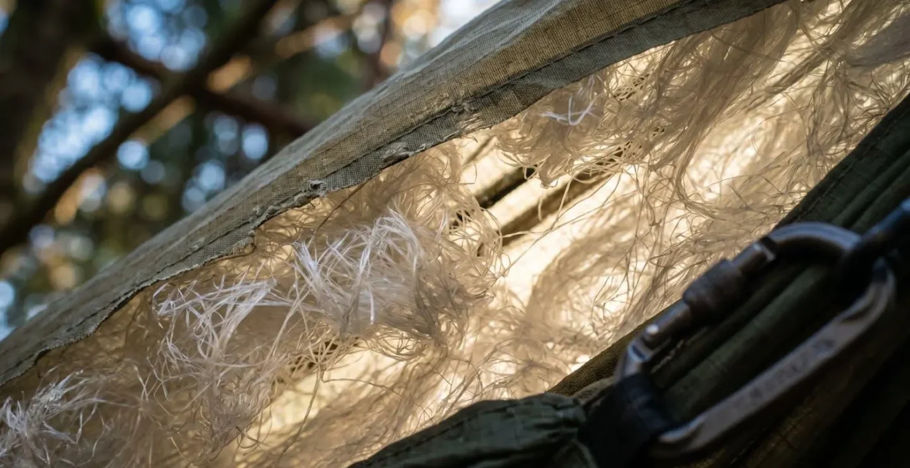 Vue macro détaillée d'un underquilt fixé sous un hamac montrant les fibres isolantes